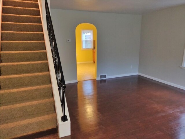 stairs featuring arched walkways, visible vents, baseboards, and wood finished floors