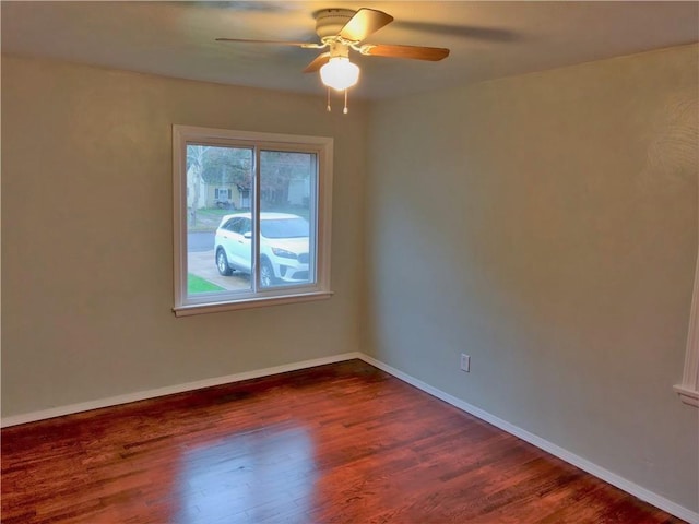 empty room featuring ceiling fan, baseboards, and dark wood-type flooring