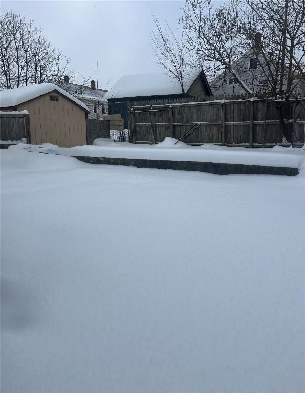 snowy yard featuring a storage shed