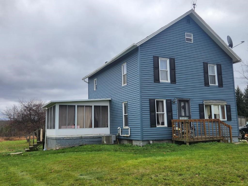 rear view of house featuring central AC, a lawn, a deck, and a sunroom