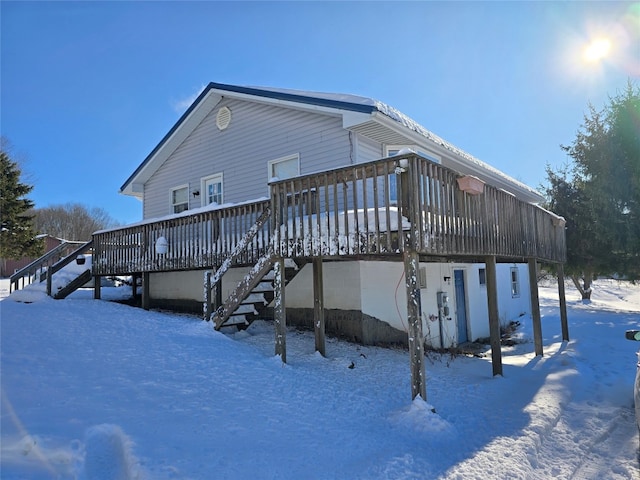 snow covered rear of property featuring a deck