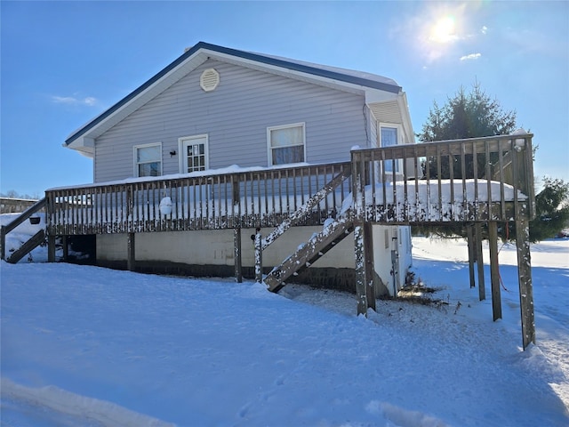 snow covered back of property featuring a wooden deck