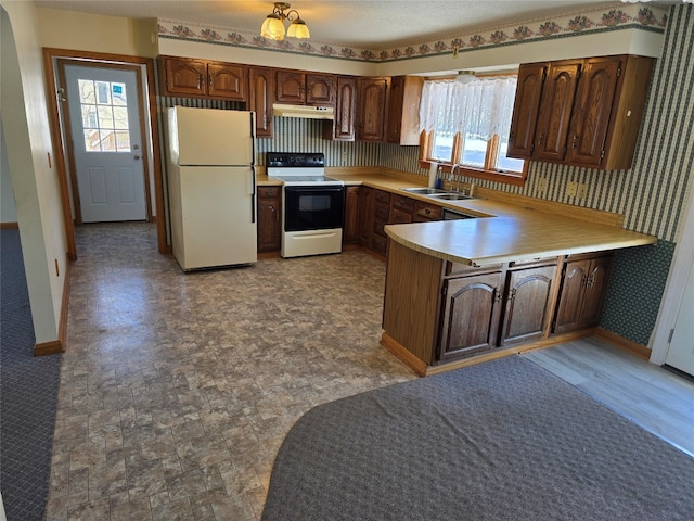 kitchen with white refrigerator, range with electric stovetop, kitchen peninsula, and sink