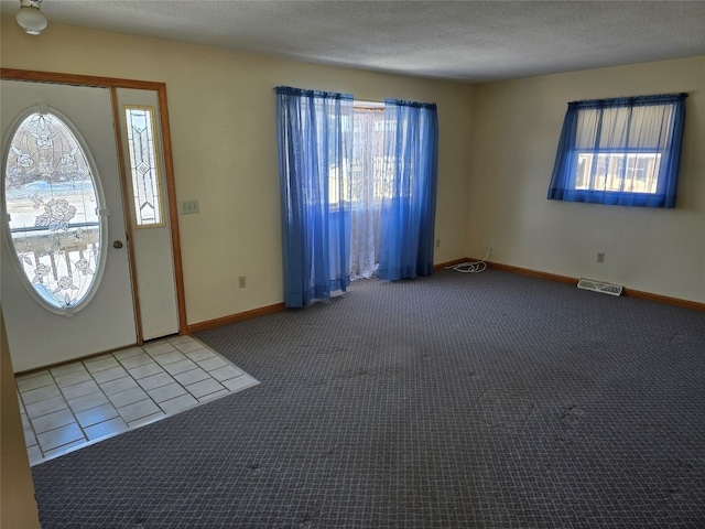 carpeted entrance foyer featuring plenty of natural light and a textured ceiling