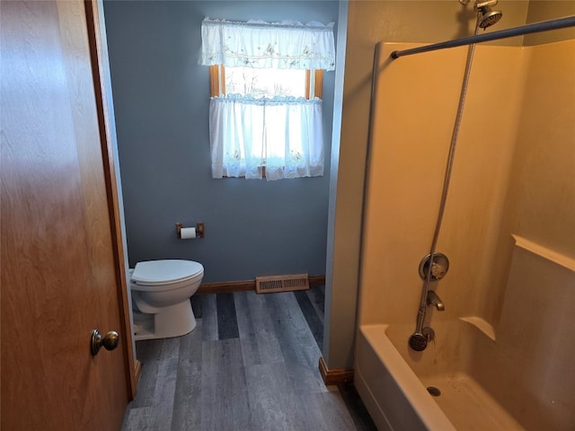 bathroom featuring wood-type flooring, toilet, and  shower combination