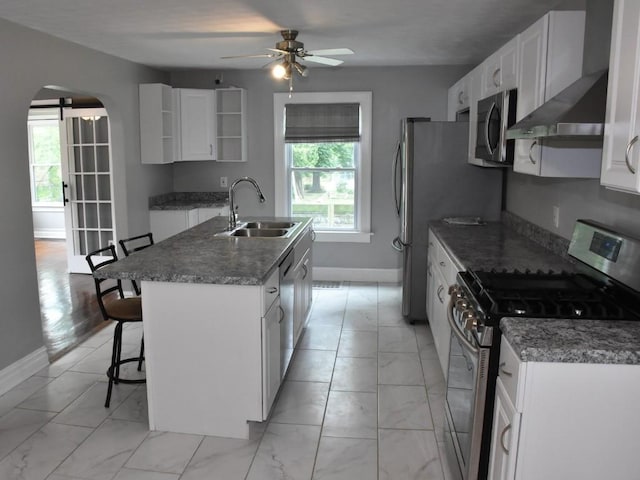 221 Locust St, Meadville, PA 16335 - kitchen featuring stainless steel appliances, wall chimney range hood, light marble finish floors, a kitchen island with sink, and a ceiling fan