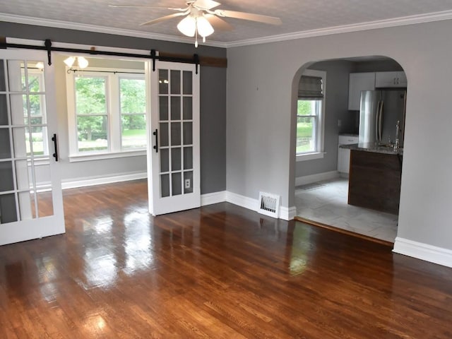 221 Locust St, Meadville, PA 16335 - empty room featuring arched walkways, a barn door, ceiling fan, wood finished floors, and ornamental molding