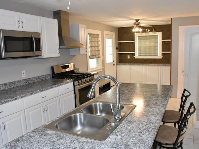221 Locust St, Meadville, PA 16335 - kitchen featuring wall chimney range hood, stainless steel appliances, a ceiling fan, open shelves, and a breakfast bar area