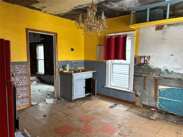 kitchen featuring a wainscoted wall, a chandelier, and a sink