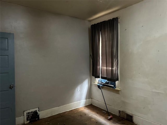 spare room featuring unfinished concrete floors and baseboards