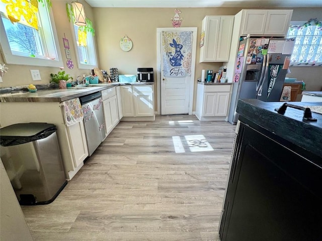 kitchen with light wood-type flooring, stainless steel appliances, a sink, and white cabinetry