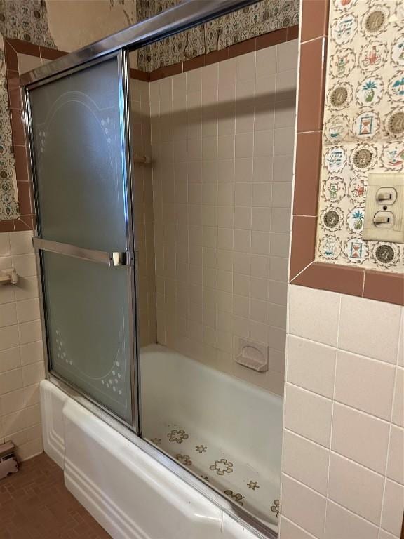 bathroom with shower / bath combination with glass door and tile walls