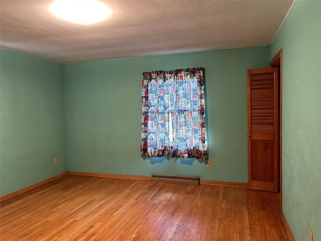 empty room with a baseboard heating unit and light wood-type flooring