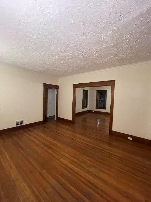 spare room featuring dark wood-type flooring and a textured ceiling