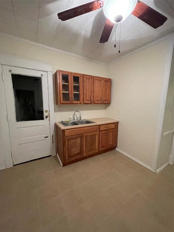 kitchen featuring ceiling fan, ornamental molding, and sink