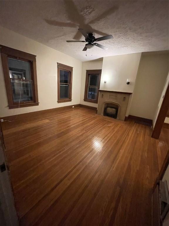 unfurnished living room with hardwood / wood-style floors, ceiling fan, and a textured ceiling