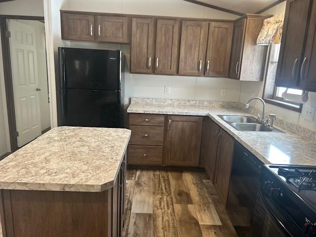 kitchen with wood-type flooring, sink, a kitchen island, and black appliances