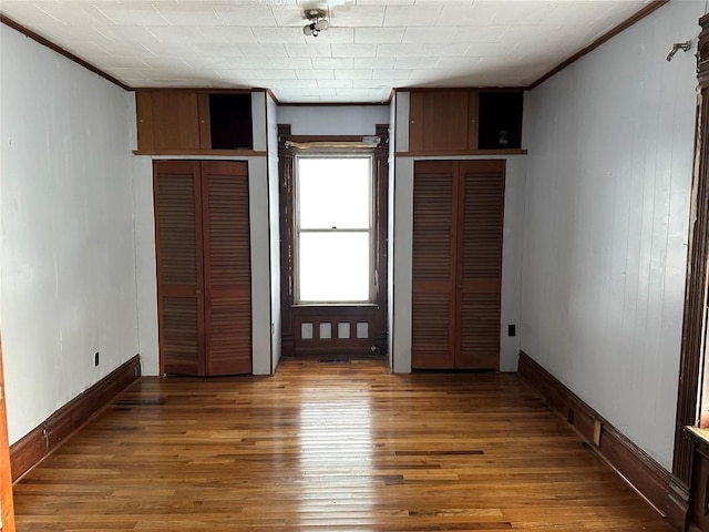 unfurnished bedroom featuring wood-type flooring and crown molding