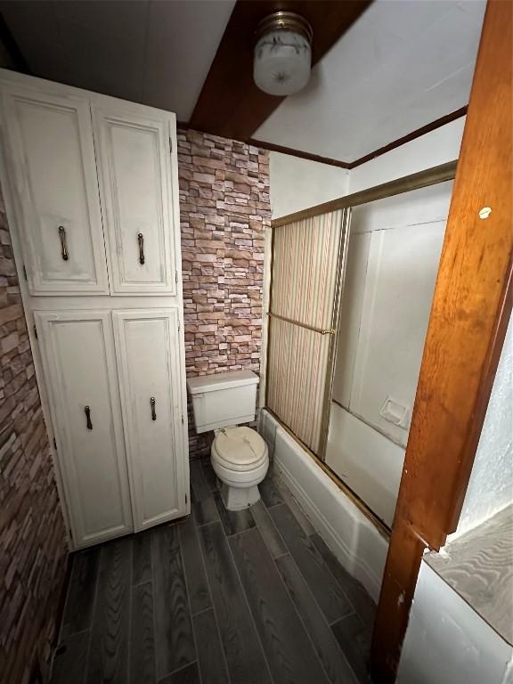 bathroom with shower / bath combination with glass door and toilet