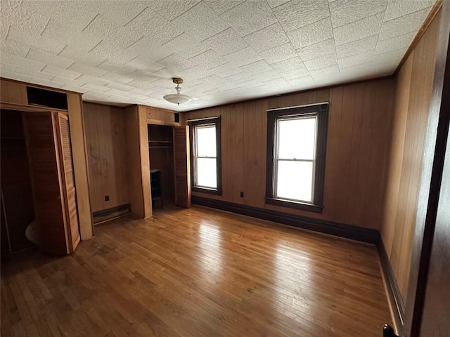 unfurnished bedroom featuring wooden walls and hardwood / wood-style flooring