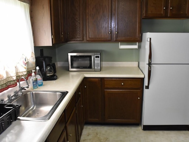 3318 County Line Rd, Cochranton, PA 16314 - kitchen featuring freestanding refrigerator, stainless steel microwave, a sink, light countertops, and dark brown cabinetry