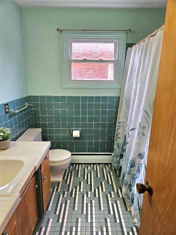 bathroom featuring tile walls, vanity, a baseboard radiator, a wainscoted wall, and toilet