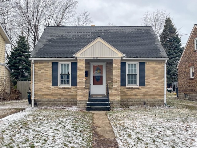 bungalow-style home with a shingled roof, entry steps, and brick siding