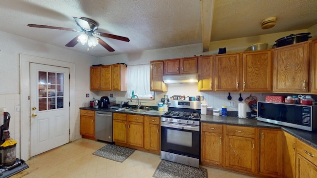 kitchen featuring decorative backsplash, a textured ceiling, stainless steel appliances, ceiling fan, and sink