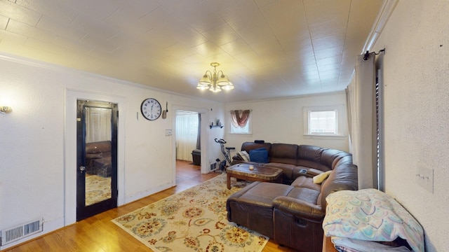 living room featuring light hardwood / wood-style floors, ornamental molding, and a chandelier