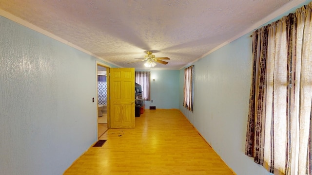 corridor with a textured ceiling and light hardwood / wood-style flooring