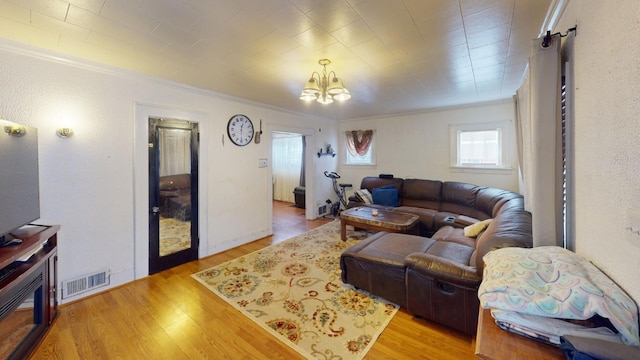 living room with light hardwood / wood-style floors, an inviting chandelier, and ornamental molding