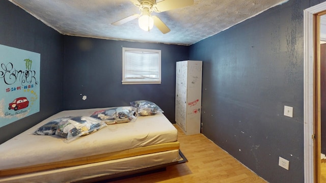 bedroom with ceiling fan, a textured ceiling, and hardwood / wood-style flooring