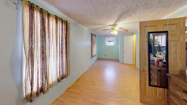 hall featuring light wood-type flooring and a textured ceiling