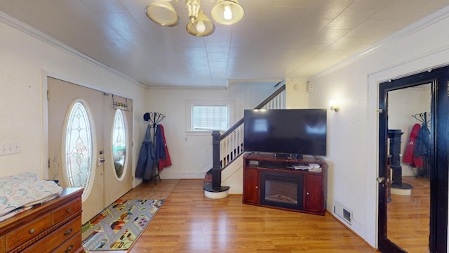 entryway with light wood-type flooring and crown molding