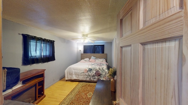 bedroom featuring ceiling fan, light hardwood / wood-style flooring, and a textured ceiling