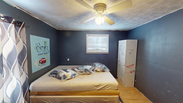 bedroom featuring ceiling fan, hardwood / wood-style floors, and a textured ceiling