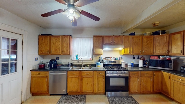 kitchen with a textured ceiling, ceiling fan, sink, and stainless steel appliances