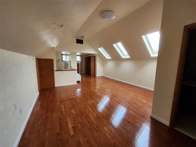 additional living space featuring hardwood / wood-style flooring and vaulted ceiling with skylight