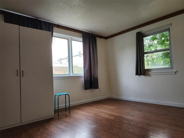 unfurnished bedroom with dark hardwood / wood-style flooring, a textured ceiling, and ornamental molding