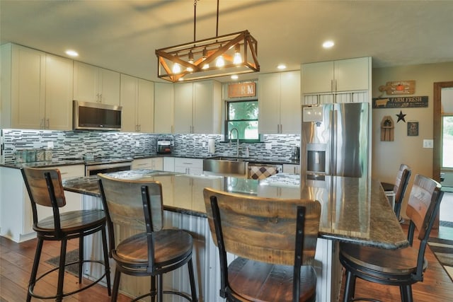 kitchen with a breakfast bar, a kitchen island, hanging light fixtures, and appliances with stainless steel finishes