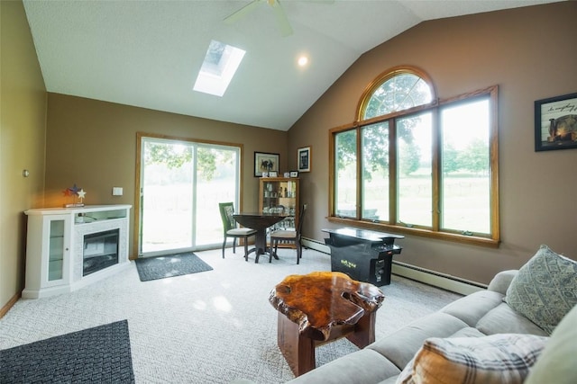 carpeted living room with vaulted ceiling with skylight, ceiling fan, a healthy amount of sunlight, and a baseboard heating unit