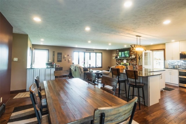 dining area featuring a wealth of natural light, dark wood-type flooring, and a textured ceiling