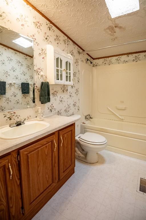 full bathroom with ornamental molding, vanity, a textured ceiling, shower / bathing tub combination, and toilet