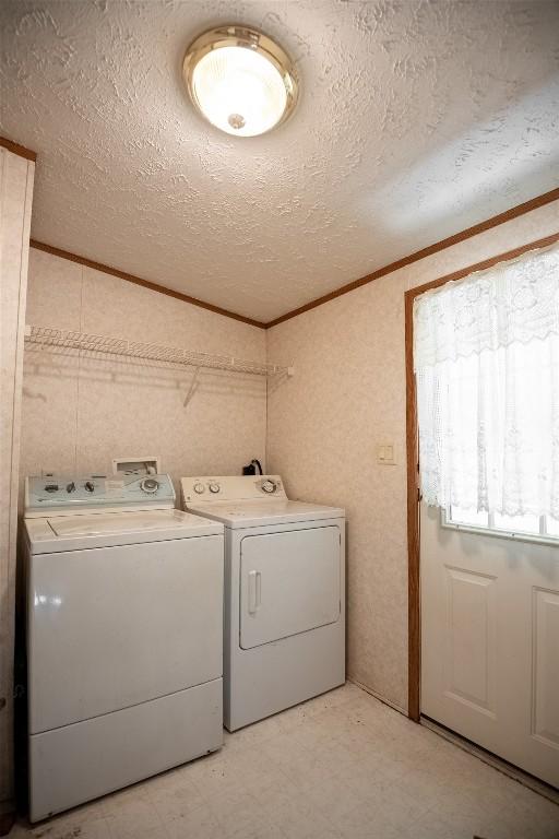 washroom featuring washer and clothes dryer, ornamental molding, and a textured ceiling