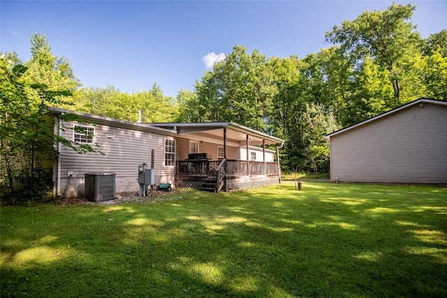 rear view of property featuring a wooden deck, a yard, and cooling unit