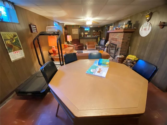 dining space featuring wood walls, a fireplace, and ceiling fan