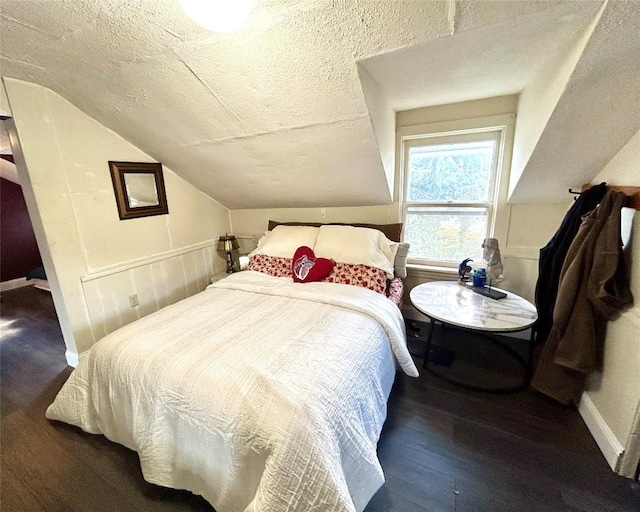 bedroom with a textured ceiling, vaulted ceiling, and dark wood-type flooring