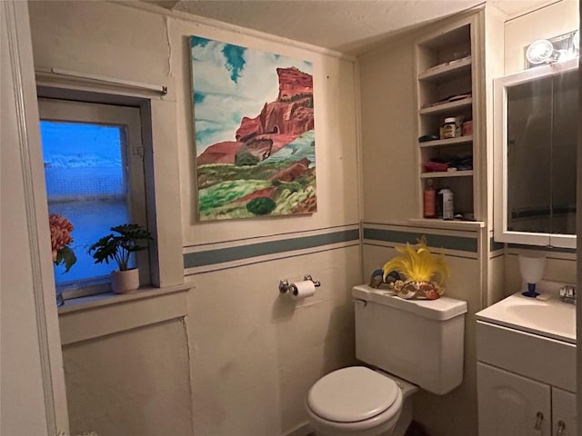 bathroom with vanity, toilet, and built in shelves