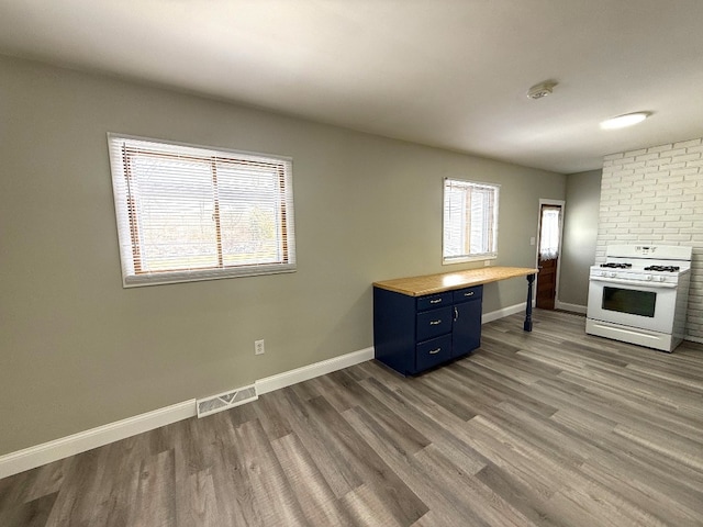 kitchen with a healthy amount of sunlight, dark hardwood / wood-style floors, white range with gas stovetop, and blue cabinets