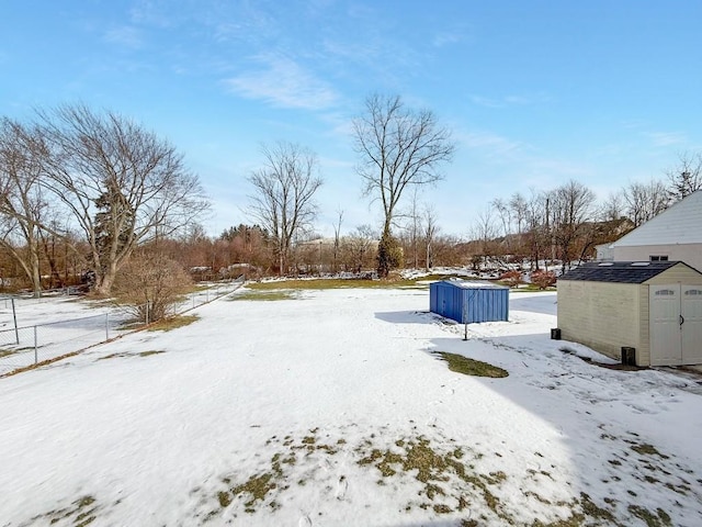 snowy yard featuring a storage shed